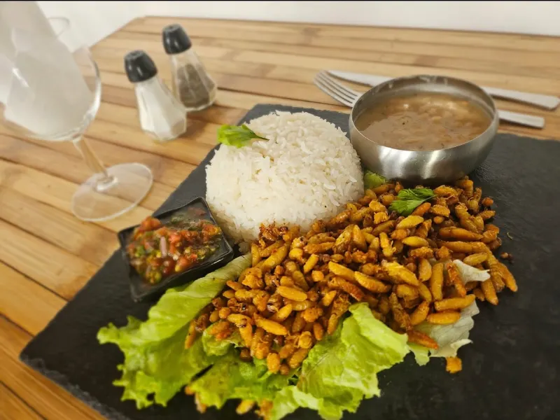 Une assiette créole sur ardoise, avec le riz, les grains et le rougail, sur une table de la salle
