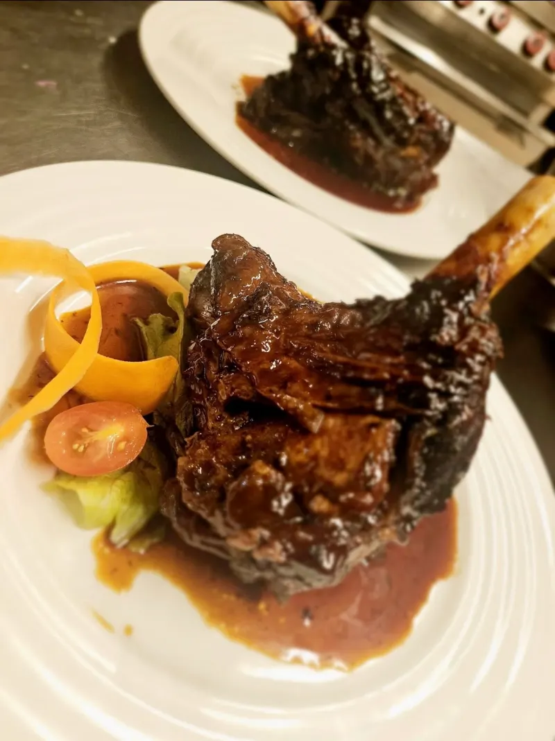 Un jarret en sauce dressé dans une assiette blanche